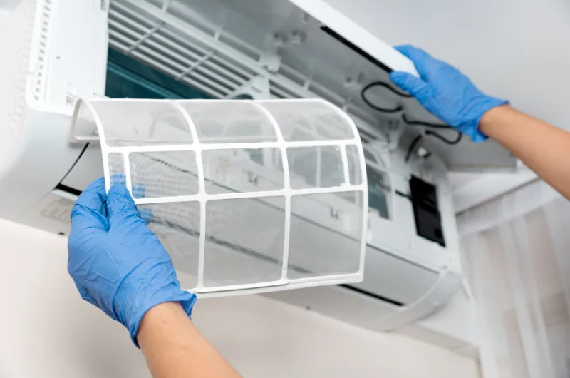 Technician cleaning the filters of a split system air conditioner
