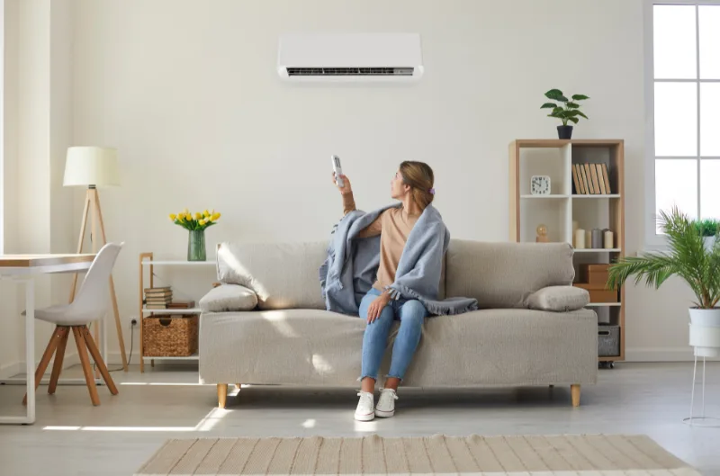 Person adjusting the heating setting on their air conditioner in winter